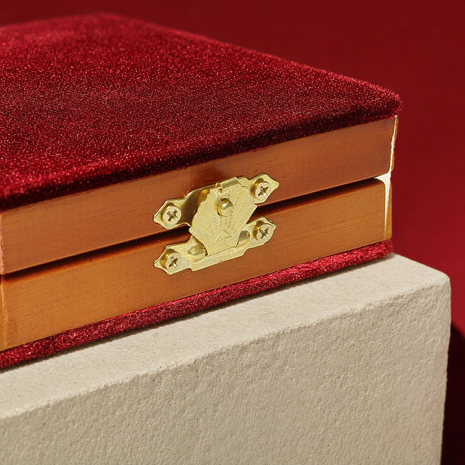 Close-up of the brass clasp on the honey pine edge of the folding diptych, crimson velvet above and below.