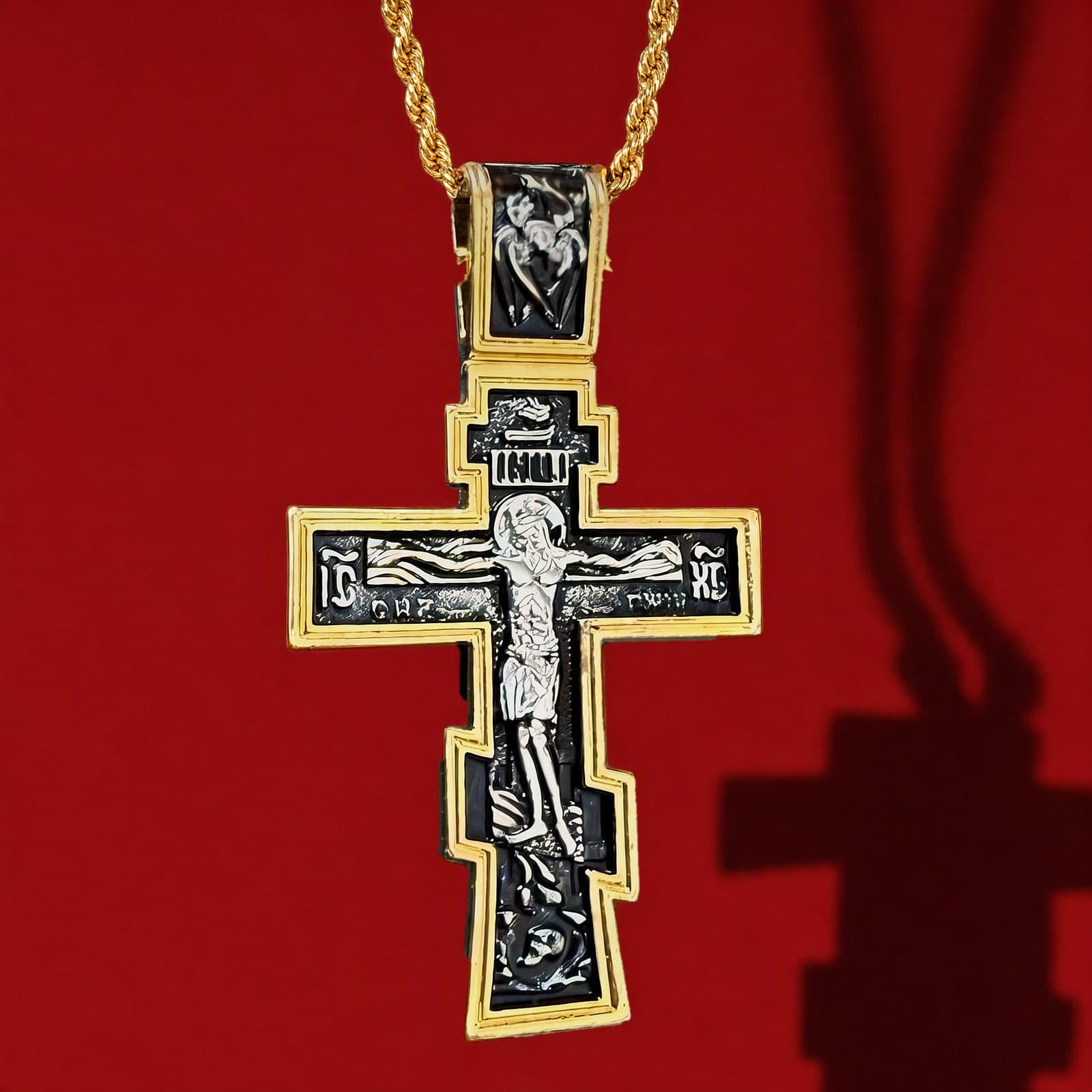 Orthodox Crucifix - Black&Gold Color - 60cm Chain - Stainless Cross: a black-and-gold stepped Orthodox crucifix with a gold-tone rim and bail on a gold-tone rope chain, against an oxblood backdrop.
