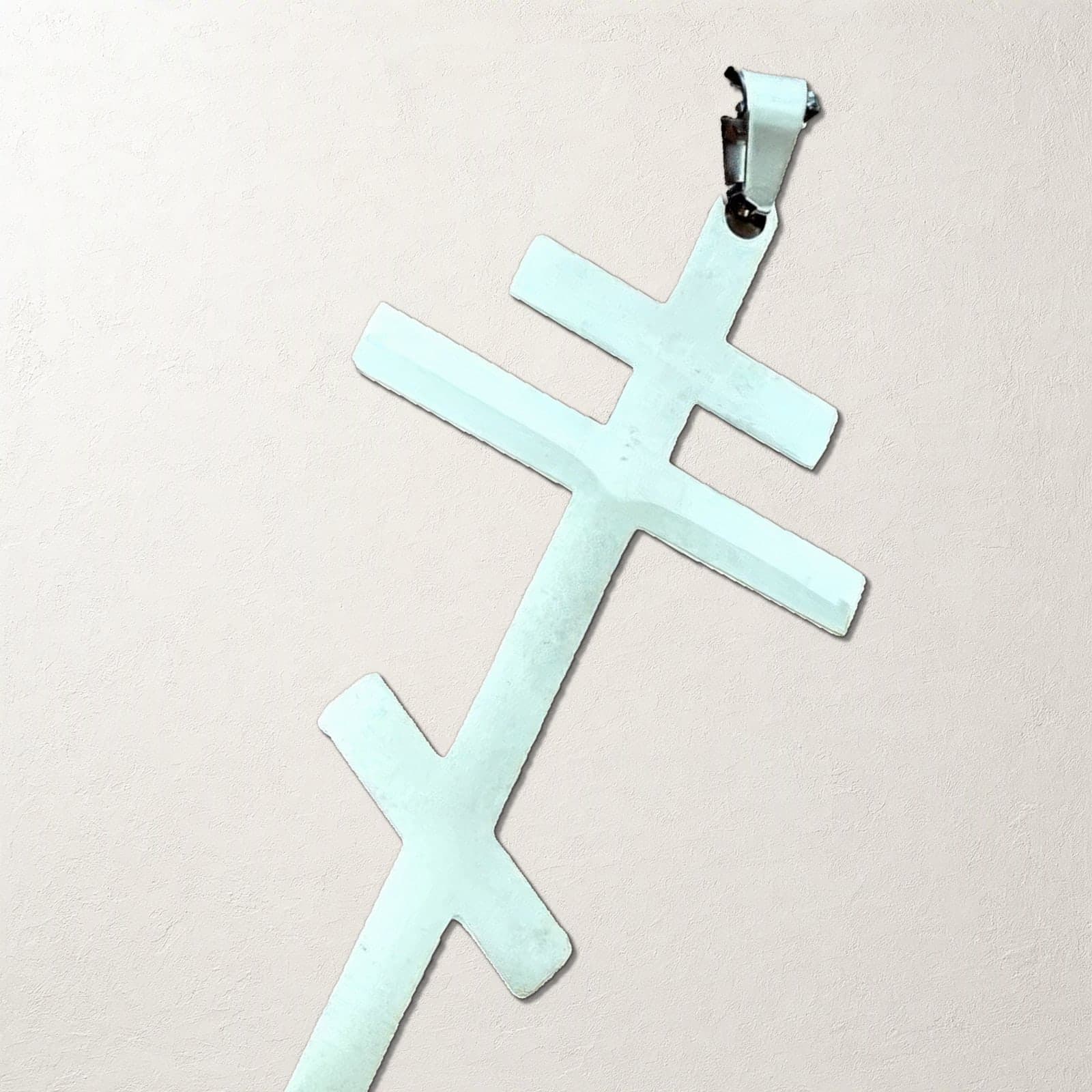 Close-up of the Orthodox Crucifix (Plain Three-Bar) - Silver Color - 60cm Chain - Stainless Steel Cross on a white plaster surface.