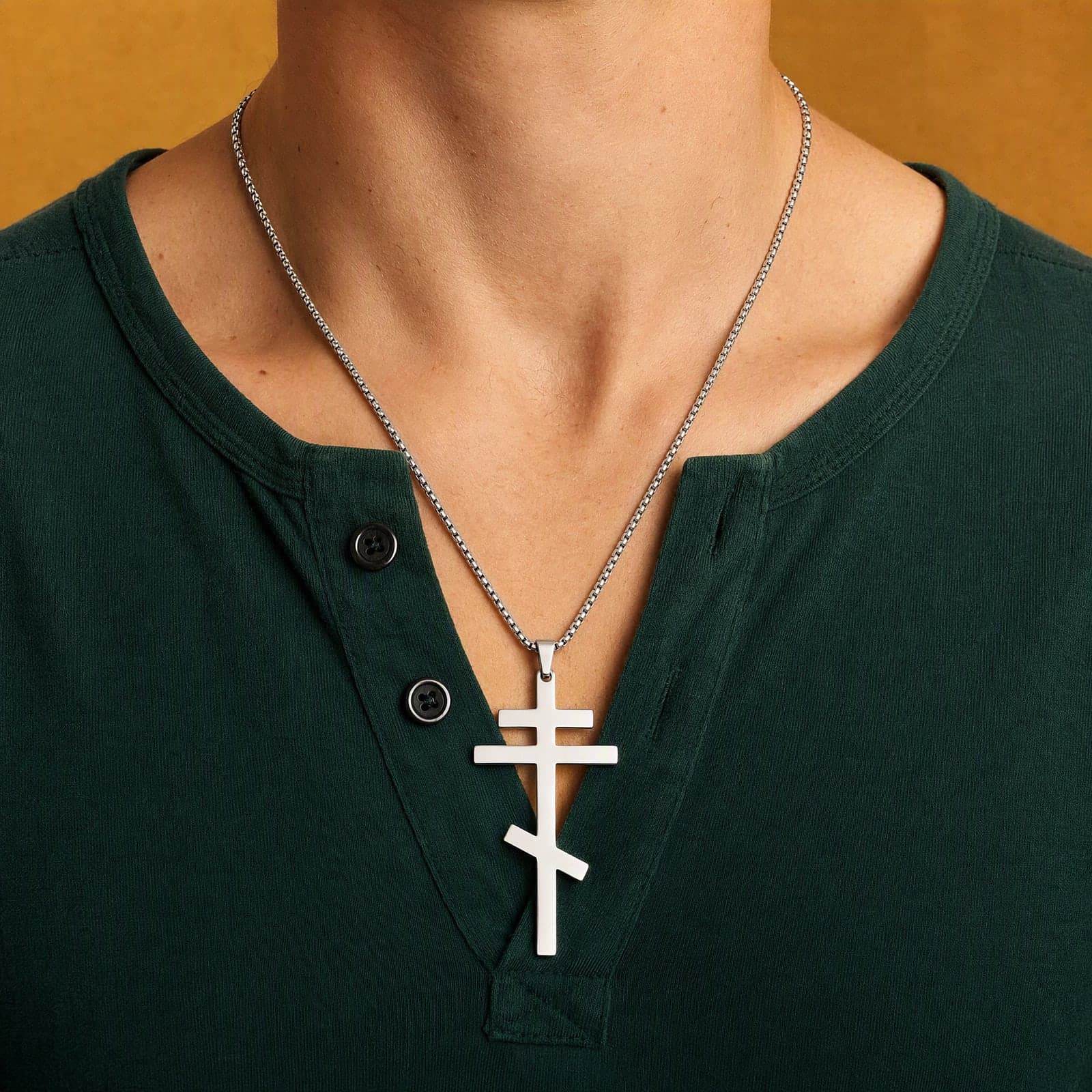 Orthodox Crucifix (Plain Three-Bar), silver-tone stainless steel cross worn at its true size (7.0 cm) on a silver-tone box chain, close crop of the chest.
