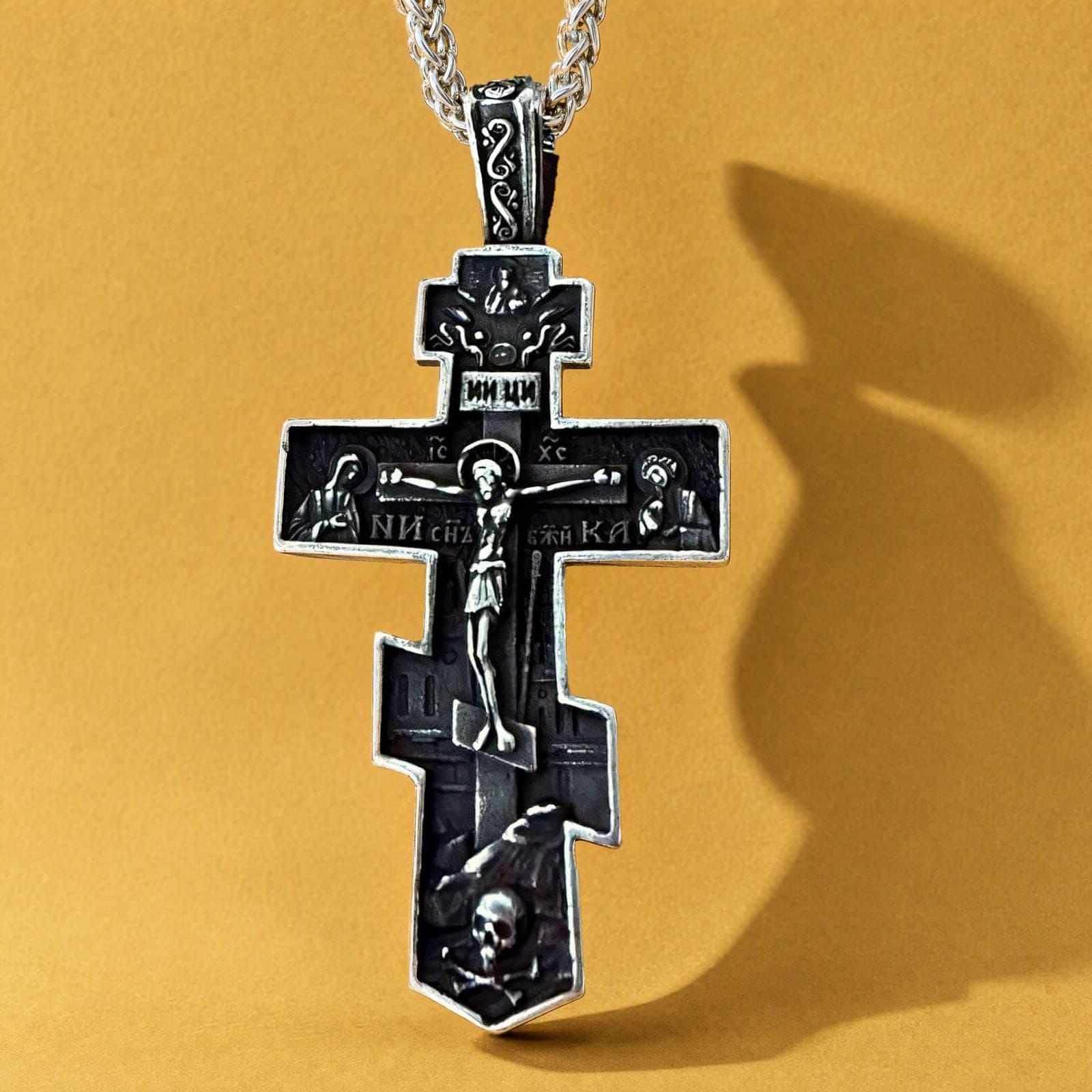 Orthodox Crucifix - Black&Silver Color - 60cm Chain - Stainless Steel Cross: a black-and-silver stepped Orthodox crucifix with an ornamented bail and blackened field on a silver-tone wheat chain, against an ochre backdrop.
