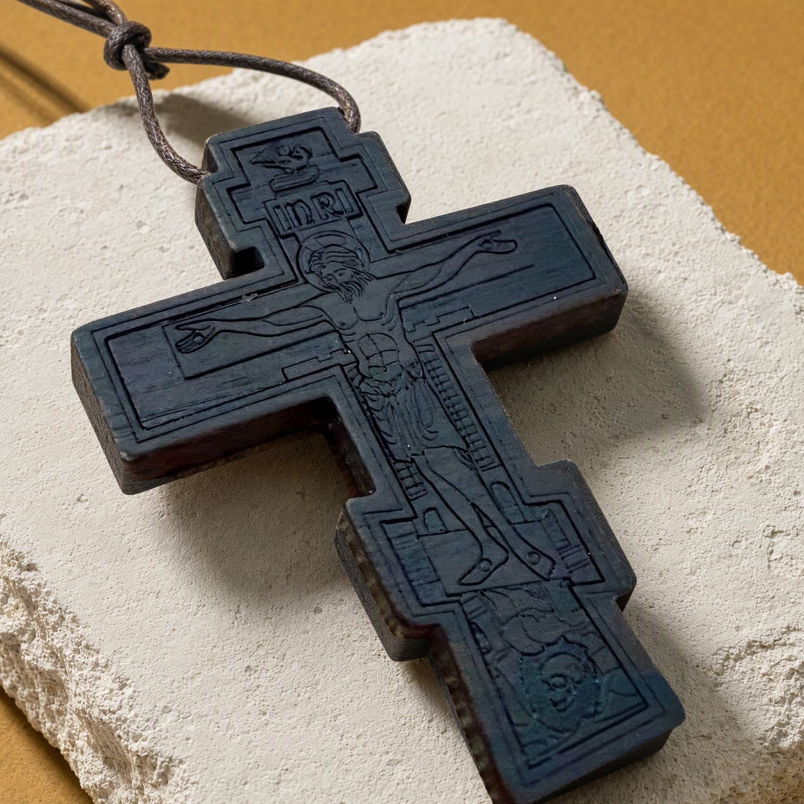 Close-up of the Orthodox Crucifix - Black Color - Wooden Cross: the relief and the bail in raking light.