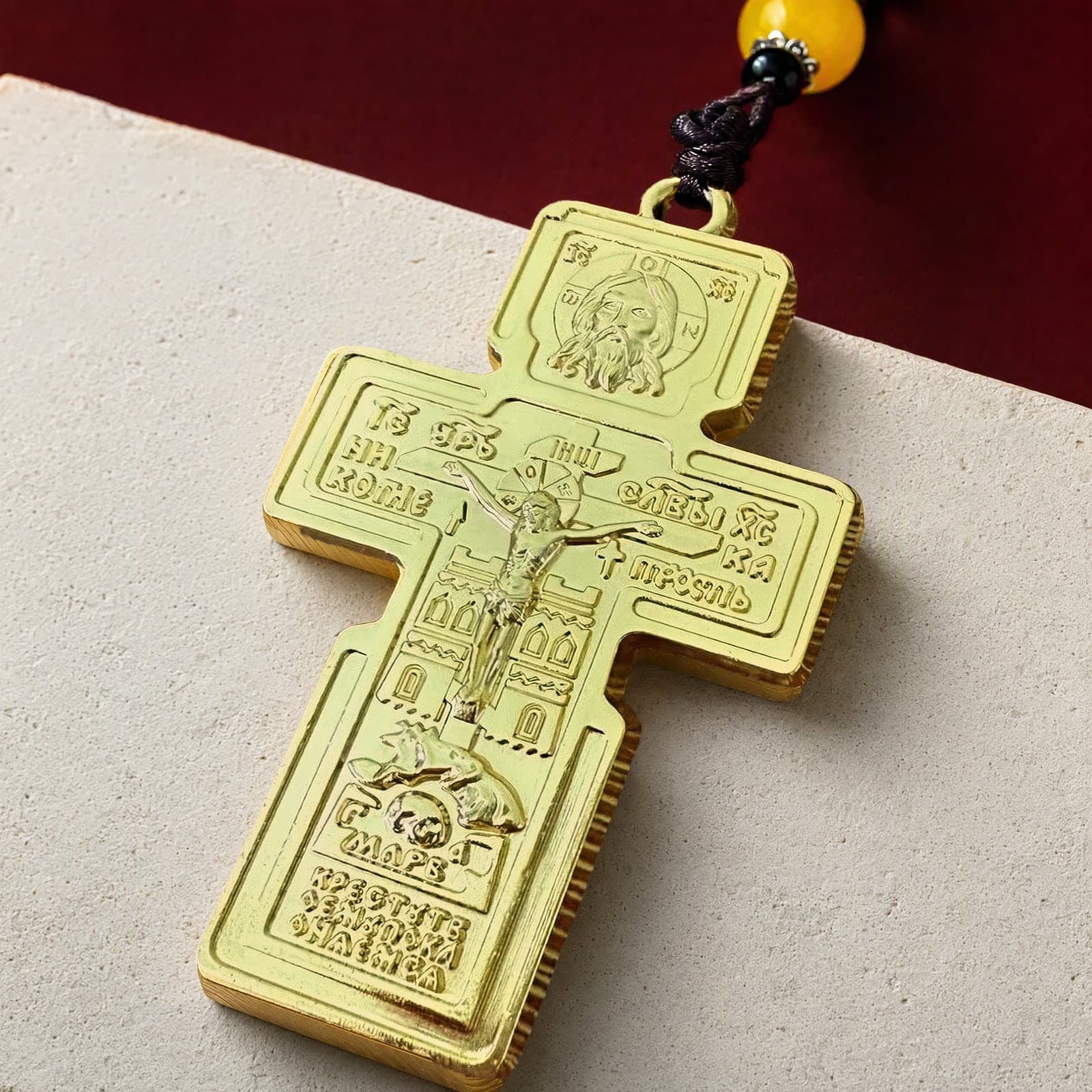 Close-up of the Orthodox Crucifix (Holy Face) - Gold Color - Stainless Steel Cross: the relief and the bail in raking light.