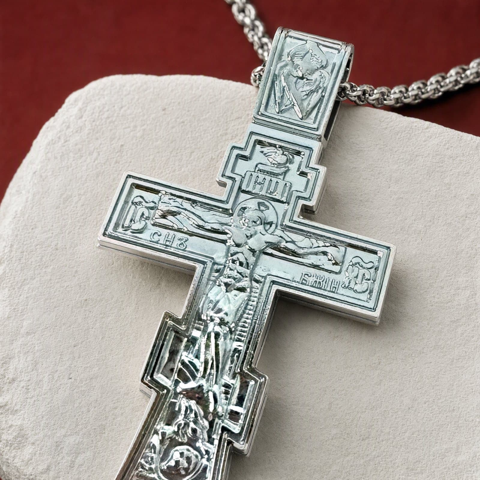Close-up of the Orthodox Crucifix (Son of God) - Silver Color - Stainless Steel Cross: the relief and the bail in raking light.