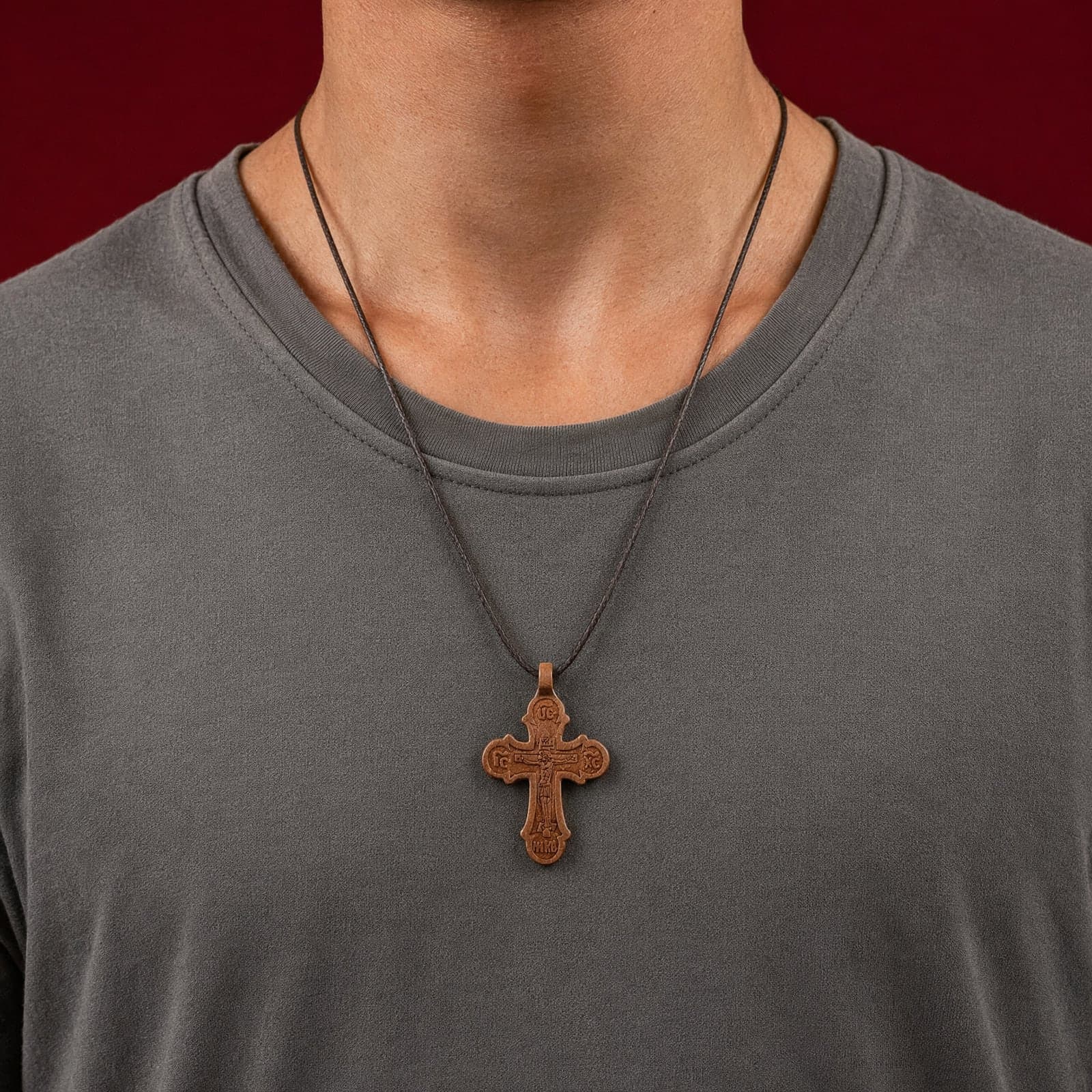 Orthodox Crucifix, wooden cross worn at its true size (5.5 cm) on a thin dark cord, close crop of the chest.