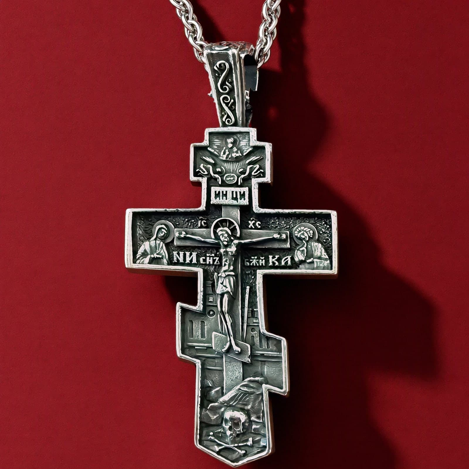 Orthodox Crucifix (Mary and St John, Dark) - Silver Color - Stainless Steel Cross 70x39mm 20.2g: a silver-tone stainless steel stepped Orthodox crucifix with an ornamented bail and deep relief of the Crucifixion on a silver-tone wheat chain, against an oxblood backdrop.