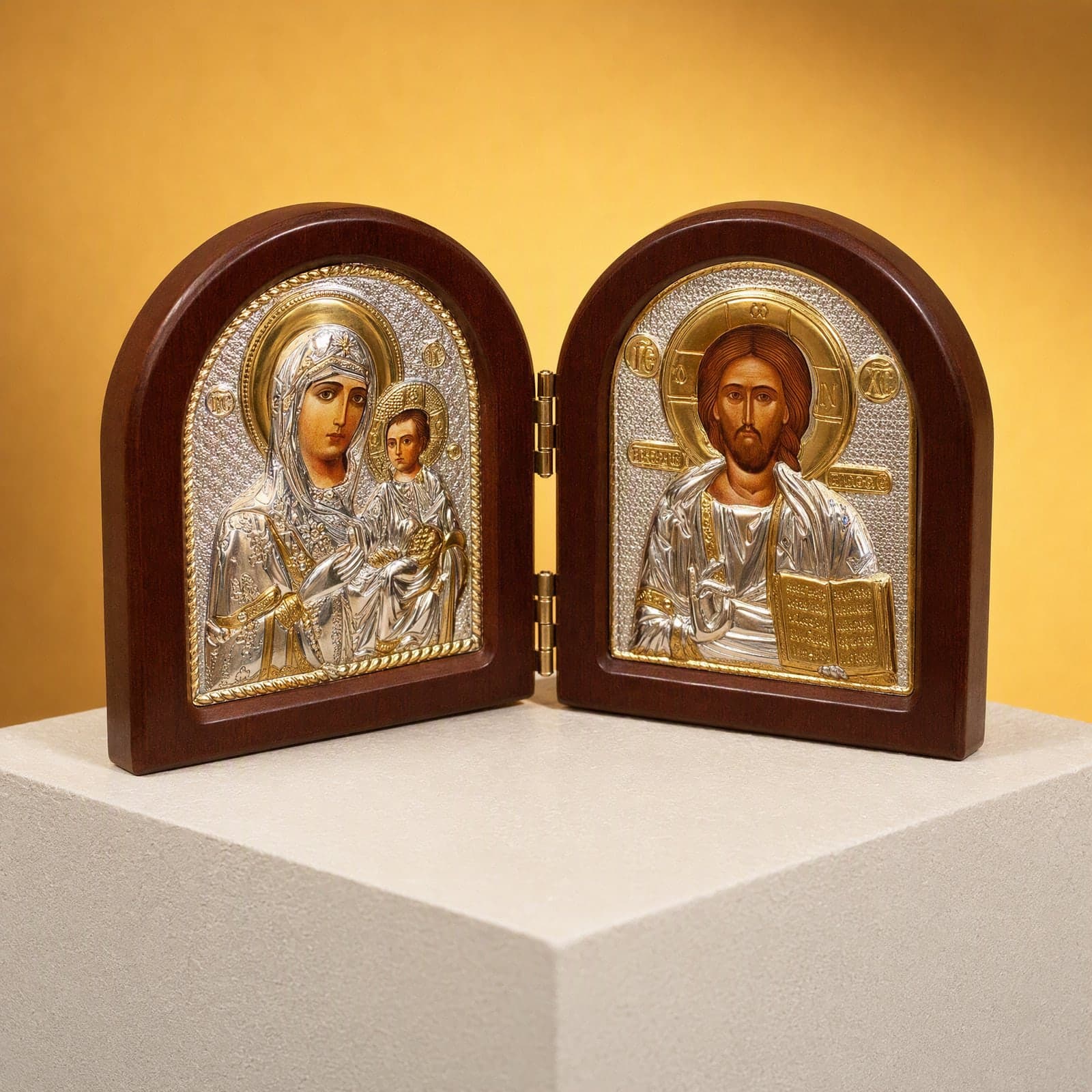 Orthodox Jesus Christ and Virgin Mary, folding wooden icon, standing on a bone plaster plinth against an ochre backdrop.