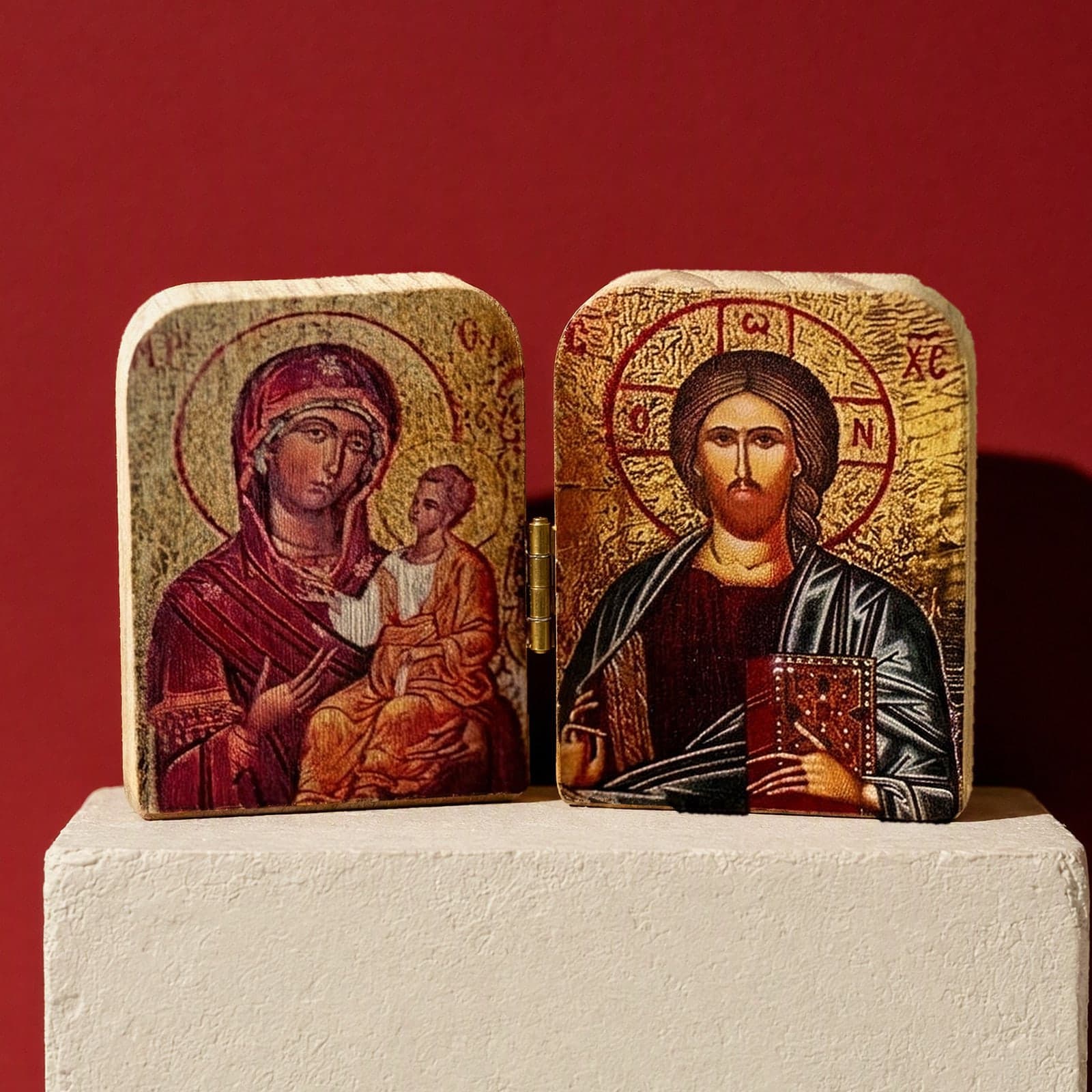 Orthodox Virgin Mary & Child, Jesus Christ - Wooden Icon: two small printed icons on wooden blocks: the Mother of God with the Christ Child and Christ, on a white plinth against an oxblood backdrop.