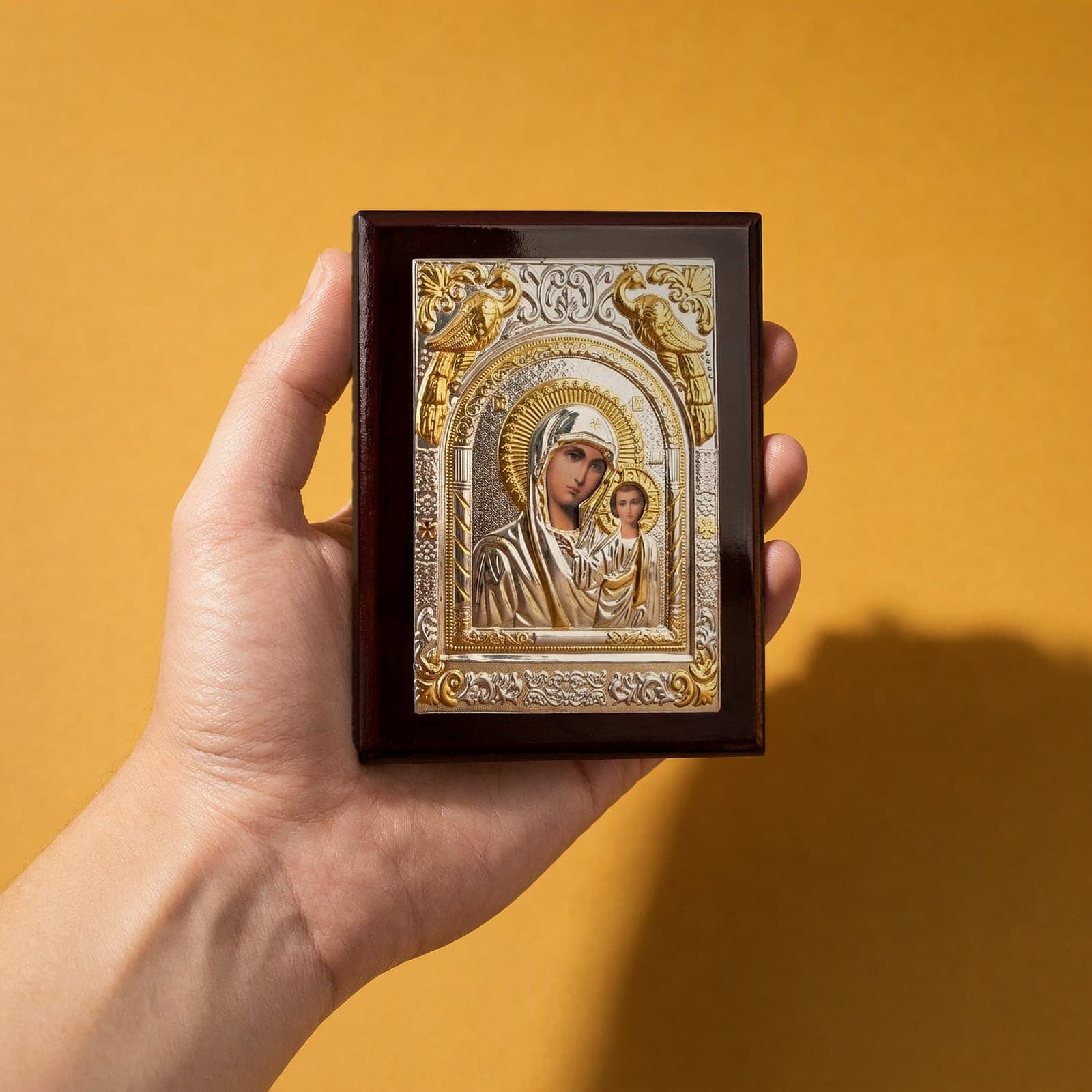 Orthodox Virgin Mary (Our Lady of Kazan, Rectangular) - Silver&Gold Color - Wooden Icon held in one hand to show its size (about 14 x 11 cm).