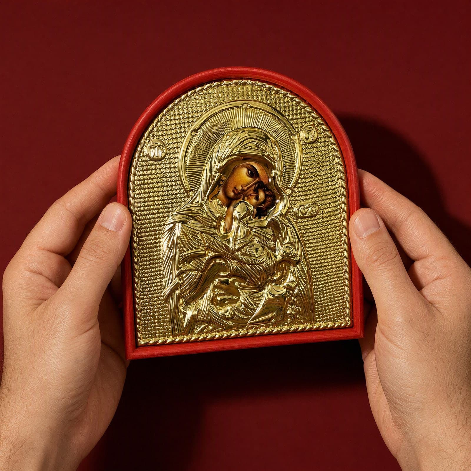 Orthodox Mother of God, gold-tone wooden icon held in both hands at its true size (14 x 11 cm).
