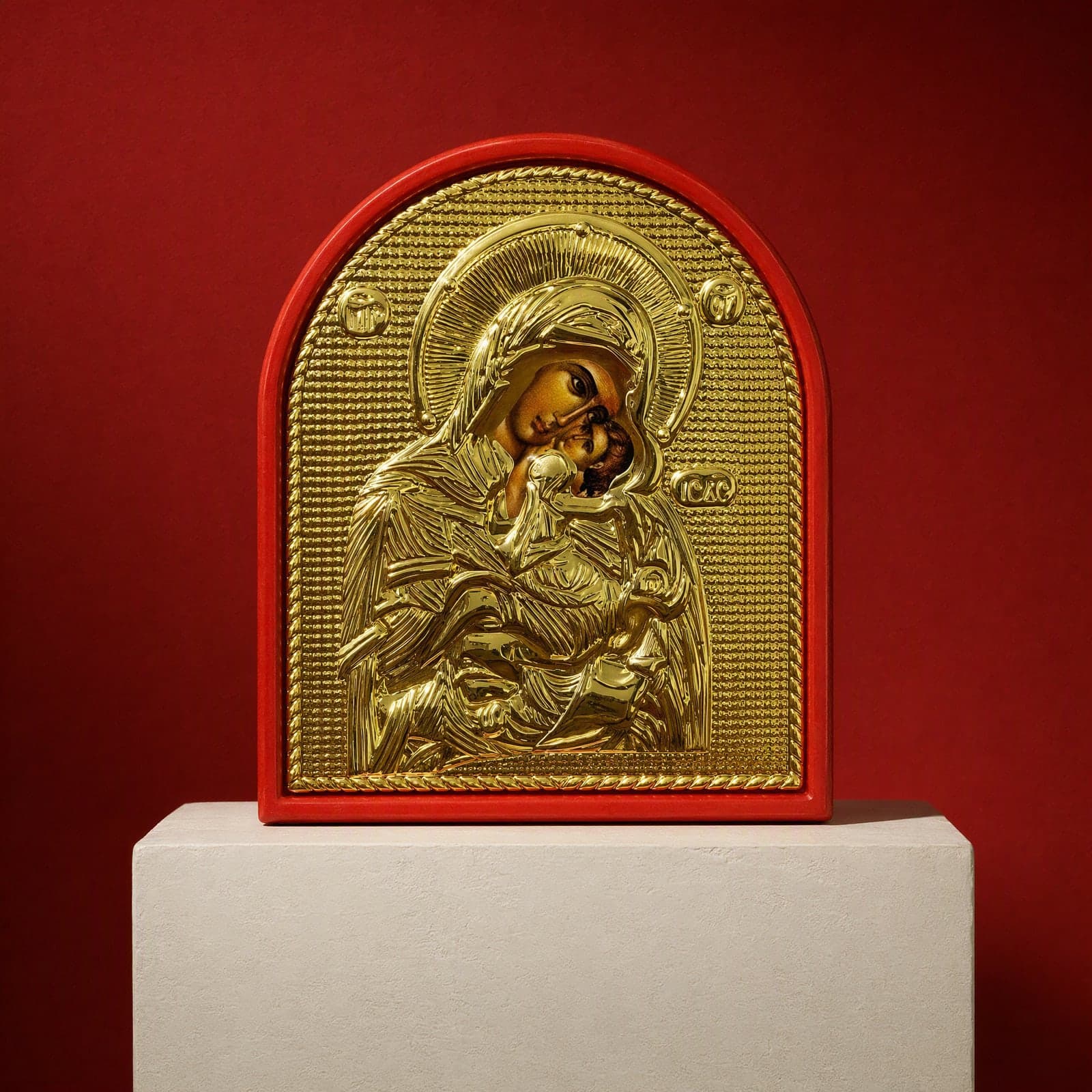 Orthodox Mother of God, gold-tone wooden icon, standing on a bone plaster plinth against an oxblood backdrop.