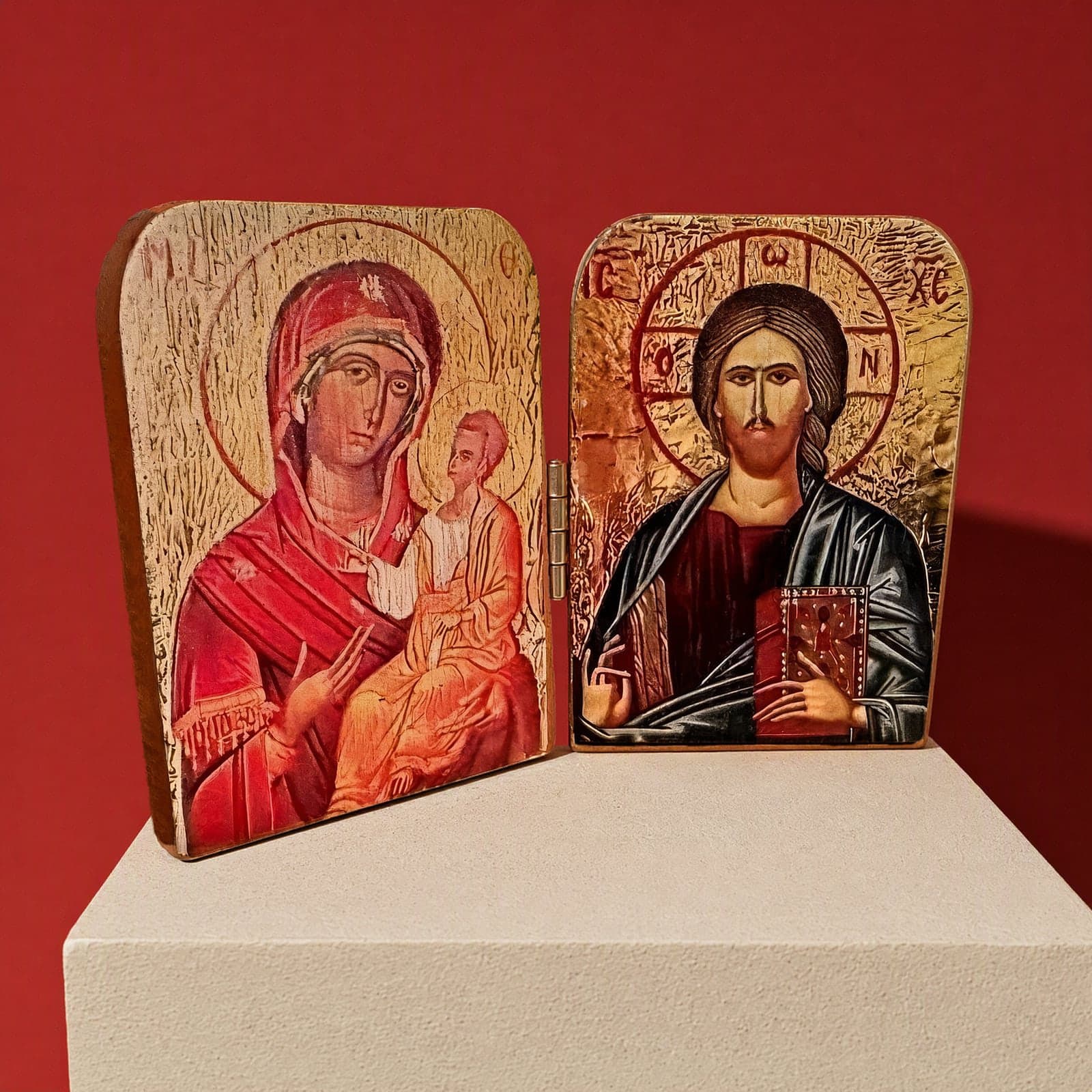 Orthodox Diptych Virgin Mary & Jesus Christ - Folding Wooden Icon: a folding wooden icon diptych with painted-style icons of the Mother of God and Christ, on a white plinth against an oxblood backdrop.
