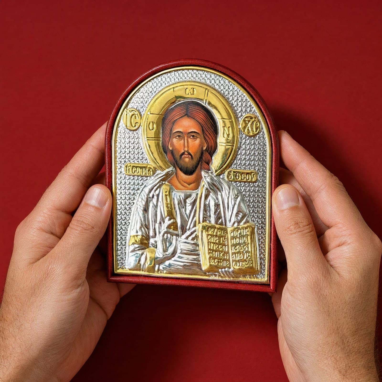 Orthodox Jesus Christ Pantocrator, silver and gold icon held in both hands at its true size (12 x 9 cm).