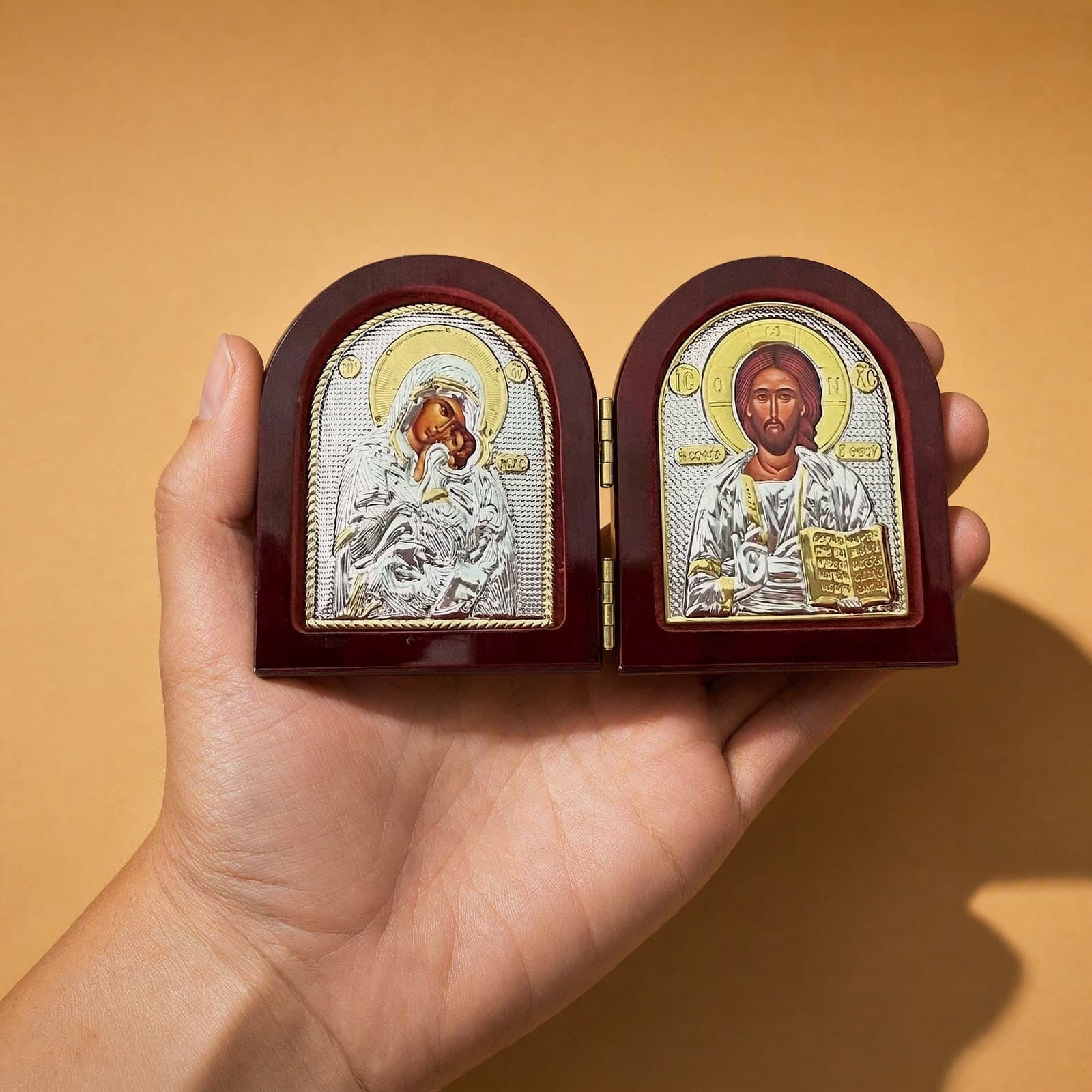 Orthodox Christ & Virgin Mary - Silver&Gold Color - Folding Wooden Icon held in one hand to show its size (about 8 x 6 cm).