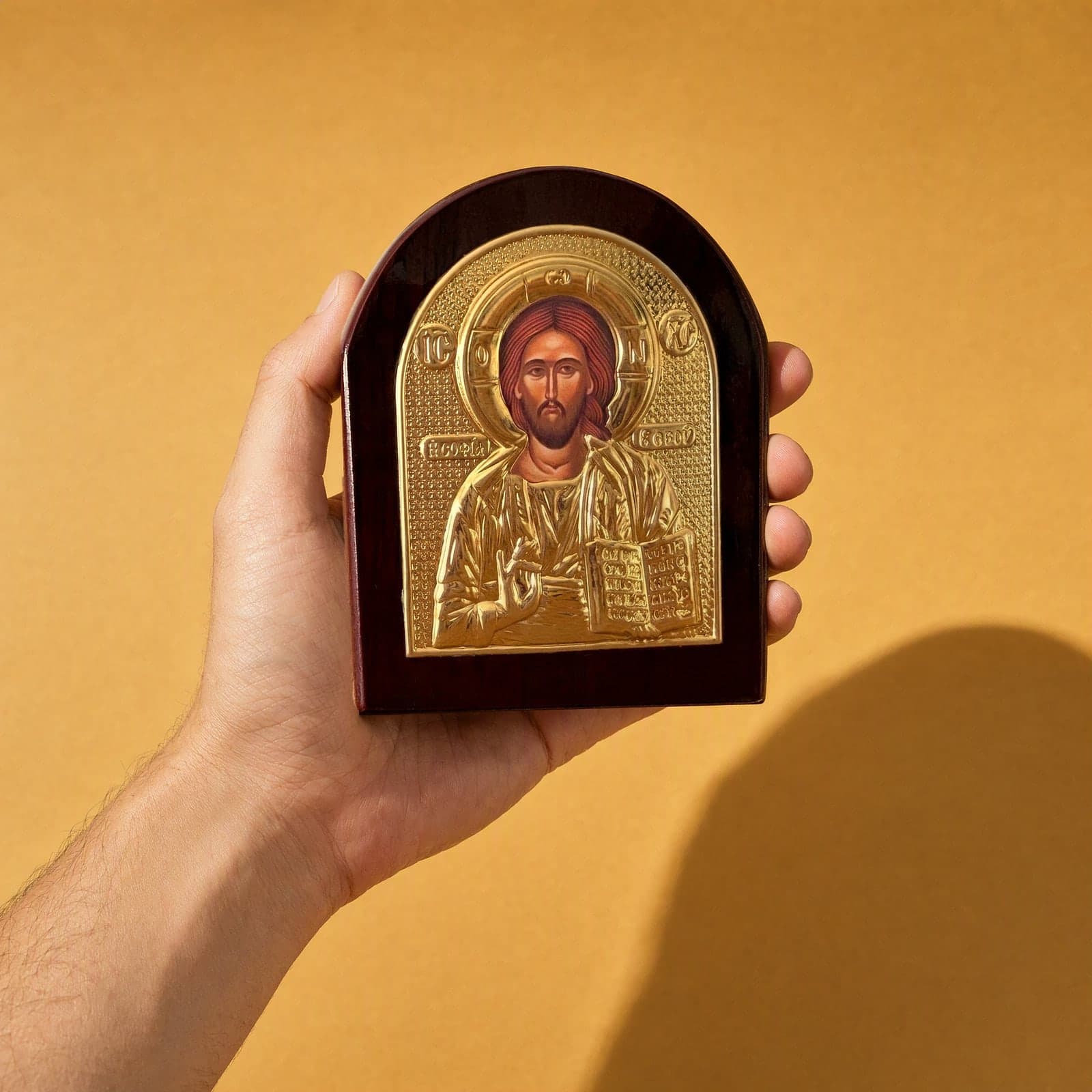 Orthodox Jesus Christ Pantocrator - Gold Color - Wooden Icon held in one hand to show its size (about 14 x 11 cm).