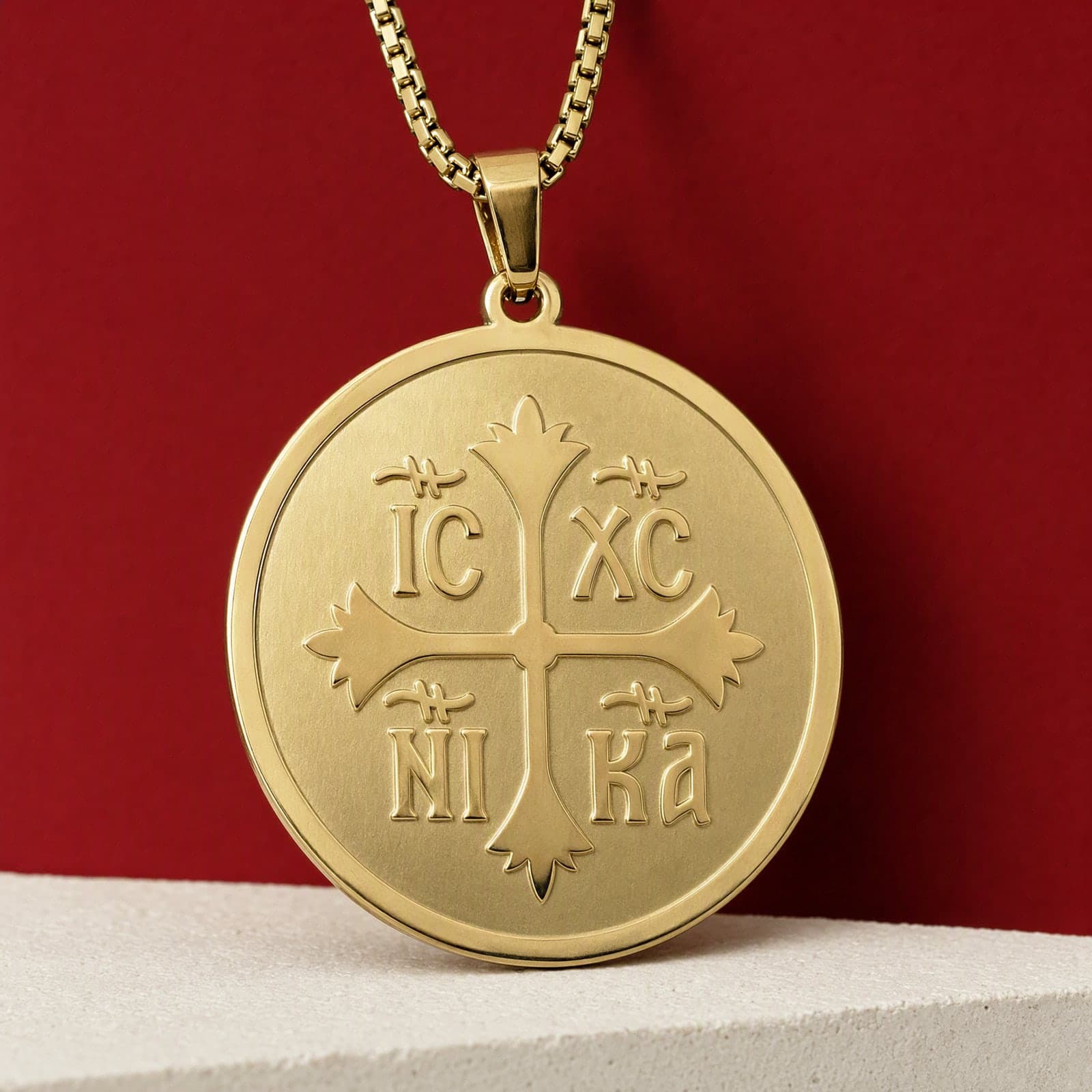 Orthodox IC XC NIKA, gold-tone stainless steel medallion: close-up of the front relief, on its chain.
