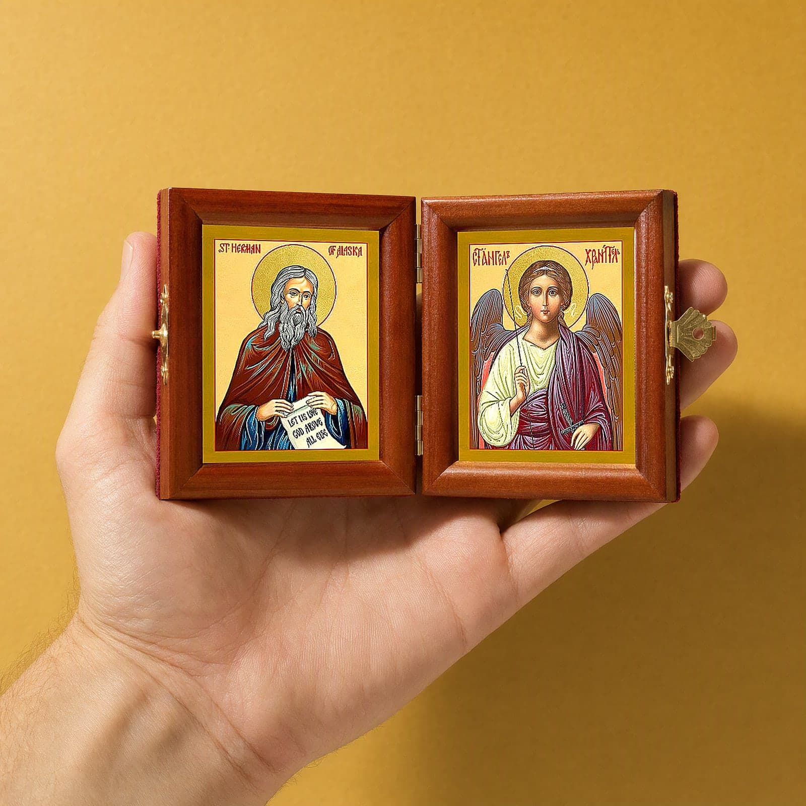 St Herman of Alaska & Guardian Angel name diptych held open in one hand to show its size: 16.5 cm wide open, about two palm widths.