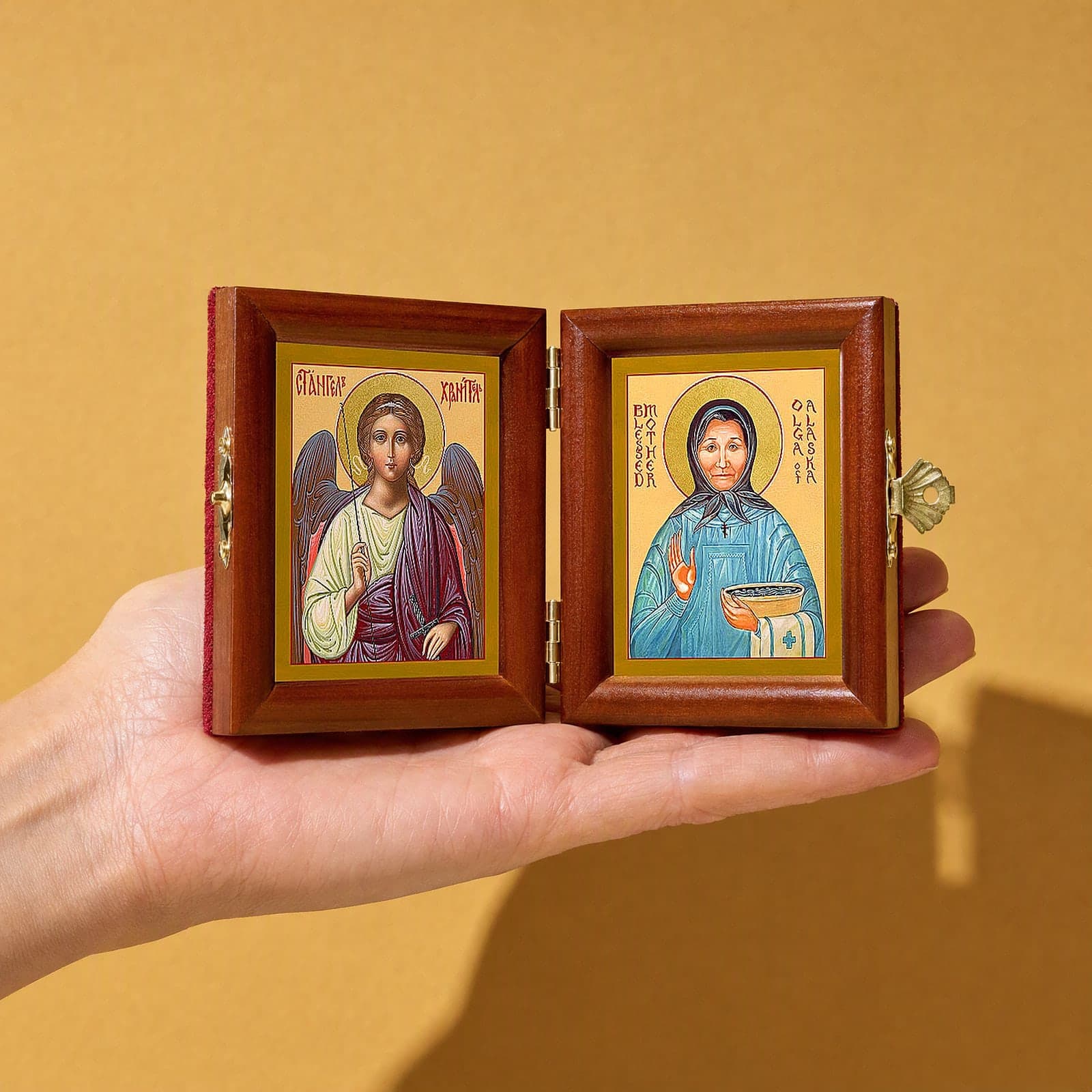St Olga of Alaska & Guardian Angel name diptych held open in one hand to show its size: 16.5 cm wide open, about two palm widths.